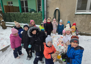 Dzieci stoją wokół kolorowego śniegu i pozują do wspólnego zdjęcia.
