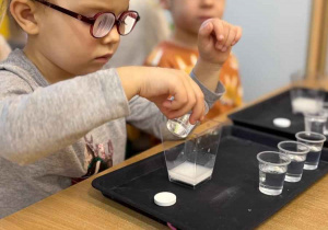 Dziewczynka leje oliwke do naczynia.