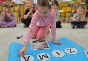 Dziecko układa litery, tworząc wyraz „zima”.