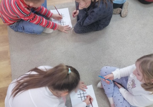 Dzieci w parach grają w „Kółko i krzyżyk”