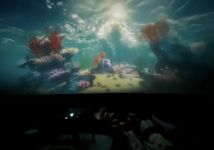 Podwodny świat z rafą koralową wyświetlany na kopule kina sferycznego.