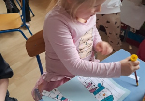 Dziewczynka przy stoliku skleja układankę.