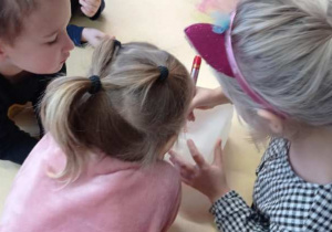 Dzieci ozdabiają mazakami karmniki zrobione z plastikowych butelek.