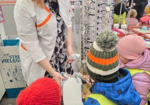 Farmaceutka wręcza dzieciom upominki podczas wizyty w aptece.