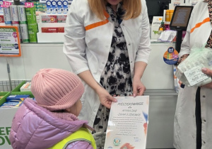 Dziewczynka z grupy przekazuje farmaceutce podziękowanie od przedszkolaków.