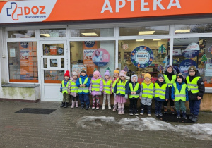 Grupa „Nutki” stoi przed wejściem do Apteki DOZ - Dbam o Zdrowie po zakończonej wycieczce.