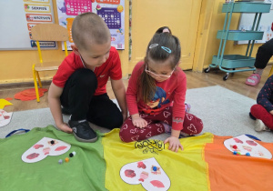 Dziewczynka i chłopiec siedzą na podłodze - grają w grę walentynkowe bingo.