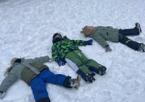 Dzieci robią aniołki na śniegu