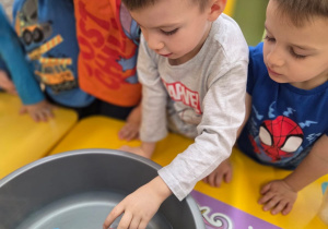 Dziecko wkłada przedmiot do wody.