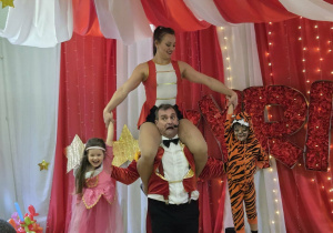 Artyści i dzieci wspólnie biorą udział w cyrkowej zabawie.