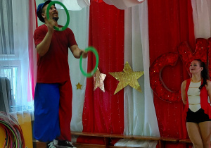 Artysta żongluje obręczami, stojąc na dużej piłce.