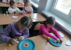 Dziewczynki wykonują misia z kolorowych talerzyków