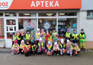 Dzieci pozują do zdjęcia przed apteką