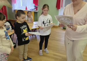 Nauczycielka rozdaje dzieciom dyplomy za udział w festiwalu.