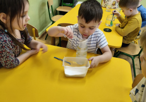 Chłopiec wsypuje sól do słoika.