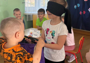 Dziewczynka za pomocą dotyku rozpoznaje przedmiot.