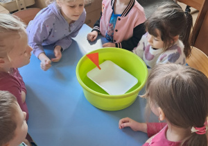 Dzieci sprawdzają, które przedmioty unoszą się na wodzie podczas zabawy badawczej.