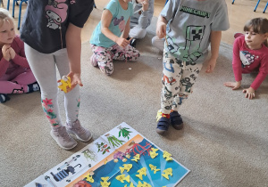 Dzieci bawią się w grę edukacyjną z papierowymi rybkami na planszy.