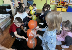 Dzieci wspólnie tworzą bałwana z balonów i papieru.