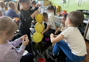 Dzieci oklejają balony papierem podczas pracy plastycznej.