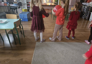 Dzieci tańczą z czerwonymi balonami podczas walentynkowej zabawy w sali.