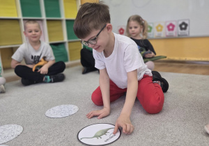 Dziecko uczestniczy w grze edukacyjnej z kartami przedstawiającymi dinozaury.