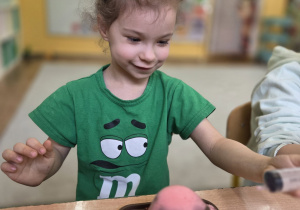 Dziewczynka obserwuje eksperyment z wybuchającym wulkanem podczas zajęć o dinozaurach.