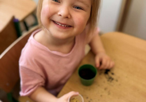 Dziewczynka trzyma w kubeczku owies.