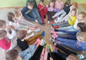 Dzieci siedząc w kole prezentują swoje kolorowe skarpetki