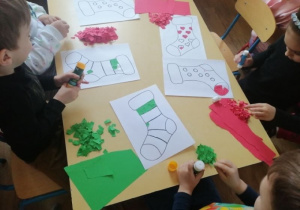 Dzieci wyklejają skarpetki czerwonym i zielonym papierem kolorowym