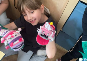 Dziewczynka prezentuje swoją skarpetkową pacynkę