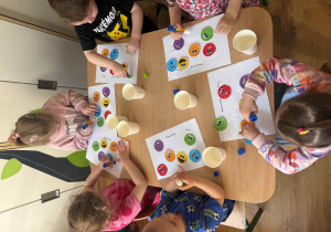 Dzieci przyklejają kolorowe buźki z emocjami.