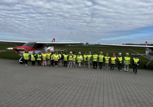 Dzieci oglądają samoloty i awionetki z bliska. Grupowe zdjęcie.