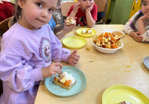 Zdjęcie przedstawiające dzieci podczas dekorowania gofrów owocami.