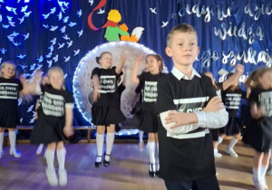 Dzieci w czarnych koszulkach z napisem NIE CHCĘ DOROSNĄĆ tańczą.