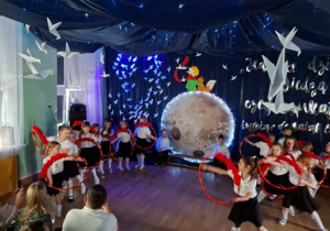 Dziewczynki tańczą z udekorowanymi różami hula hopami.