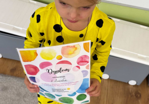 Dziewczynka trzyma dyplom za dzień kropki.